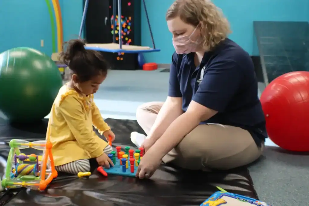 Child working on finger and hand coordination during a pediatric occupational therapy session focused on fine motor and gross motor skill development.