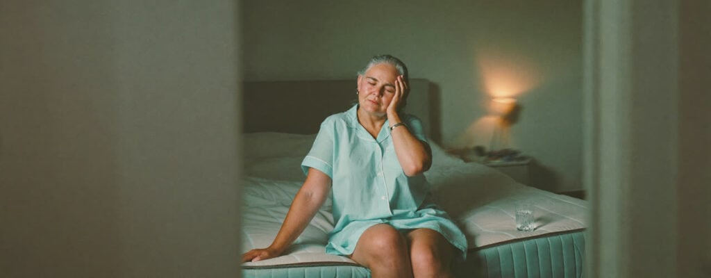 Woman sitting on edge of bed with dizziness from BPPV vertigo - treated at Synergy Therapeutic Group, Carbondale IL